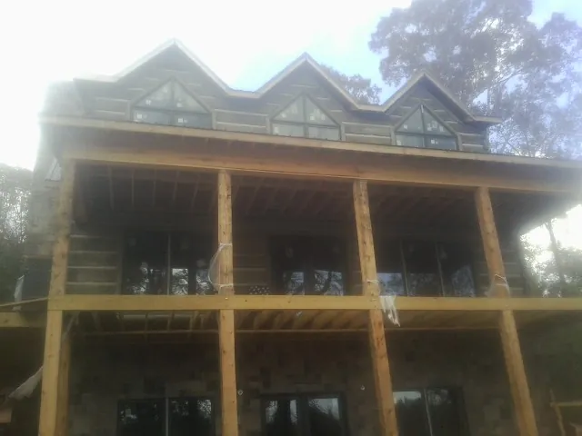 Dormers and porch framing on a large log home under construction — Roof Coating work by our crew in New Braunfels