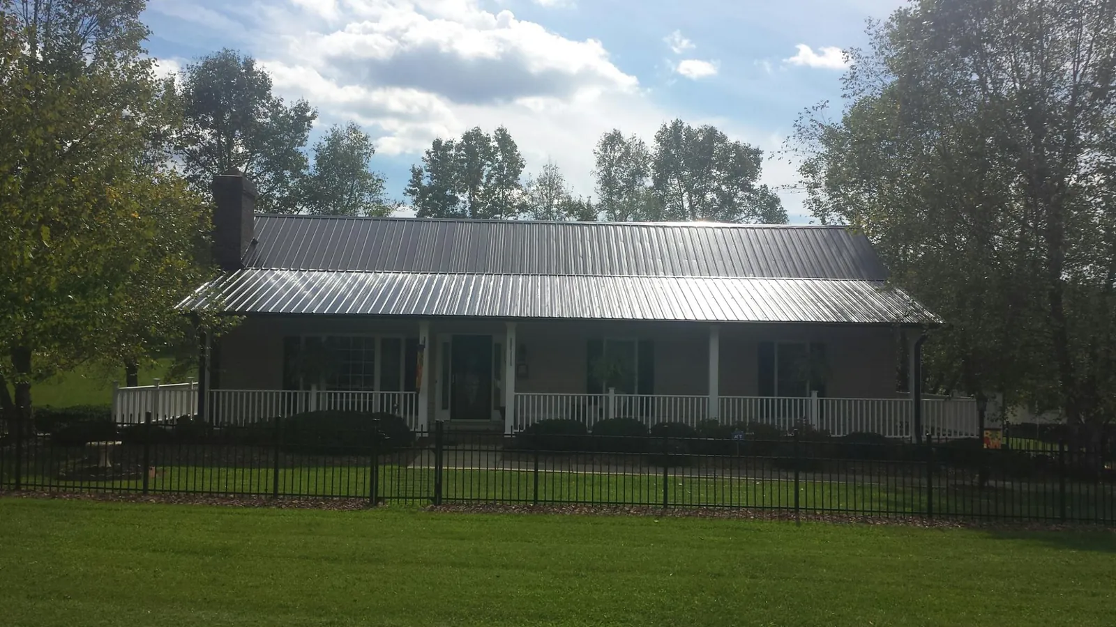 Gray metal roof on a brick ranch with a full width front porch — Gutter Guard Installation work by our crew in New Braunfels