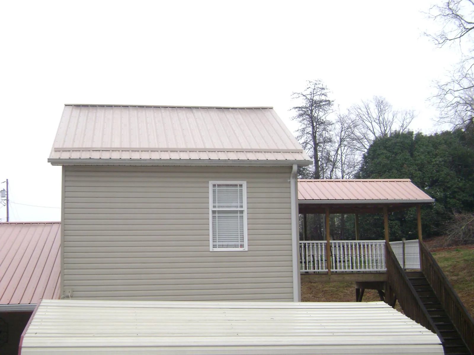 Tan metal roofs on a two story addition and attached porch, from a Roof Replacement job in New Braunfels