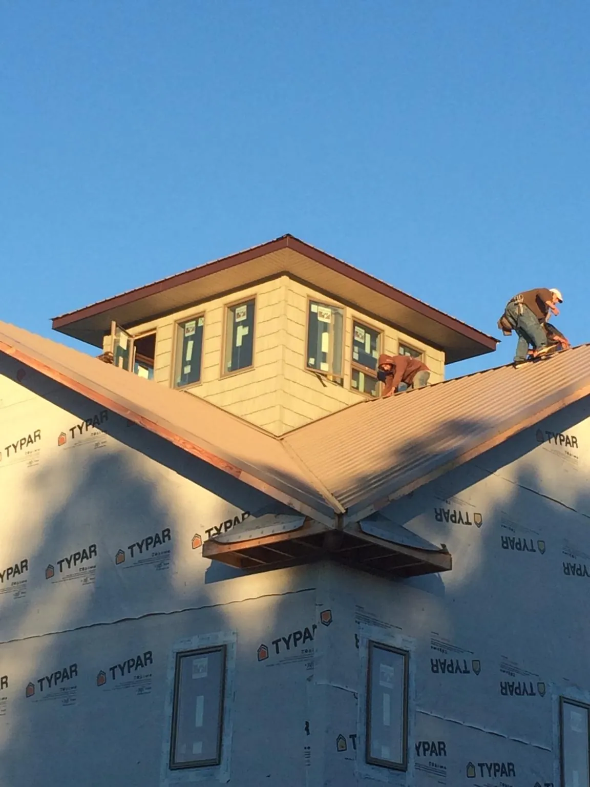 Roofers working around a rooftop cupola on a new metal roof at sunset — Roof Waterproofing in New Braunfels by Roofing Brothers